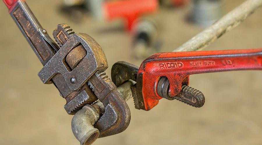 Close-up photograph of two wonderfully-worn wrenches clamped onto a pipe that’s floating in mid-air